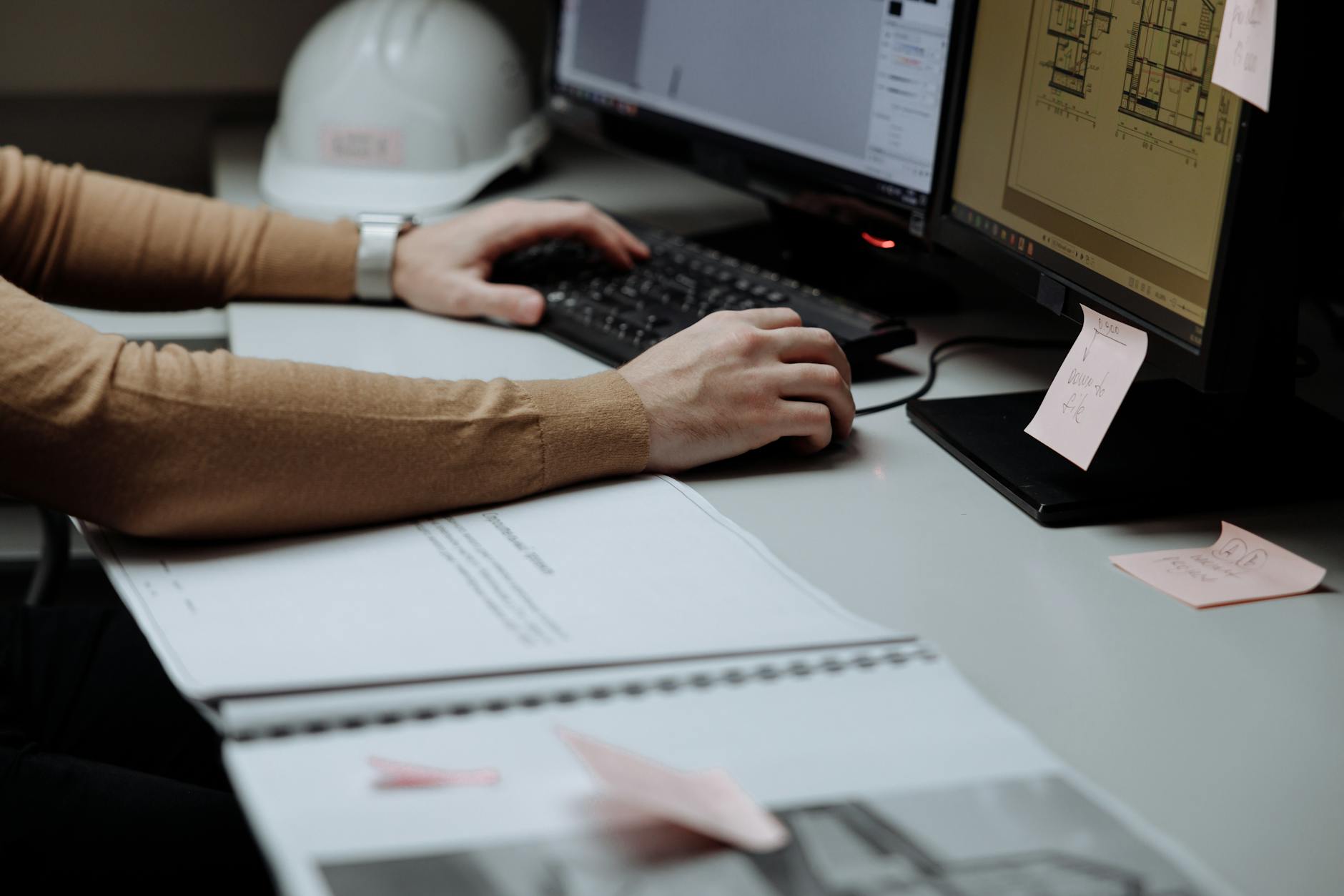 Ingegnere civile in ufficio con planimetrie e software gestionale