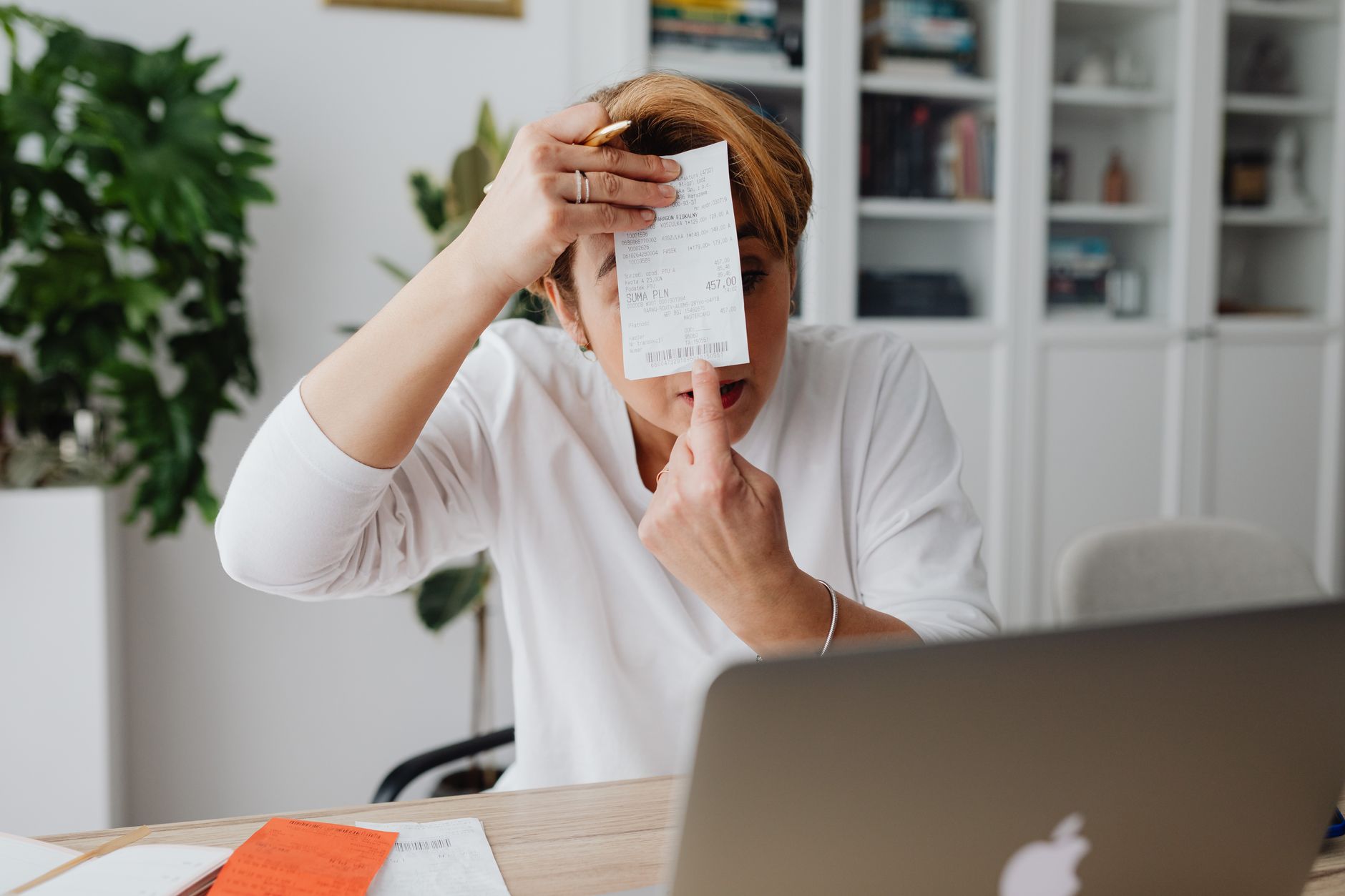Contabile in ufficio che lavora a riconciliazione fatture passive su laptop con documenti cartacei