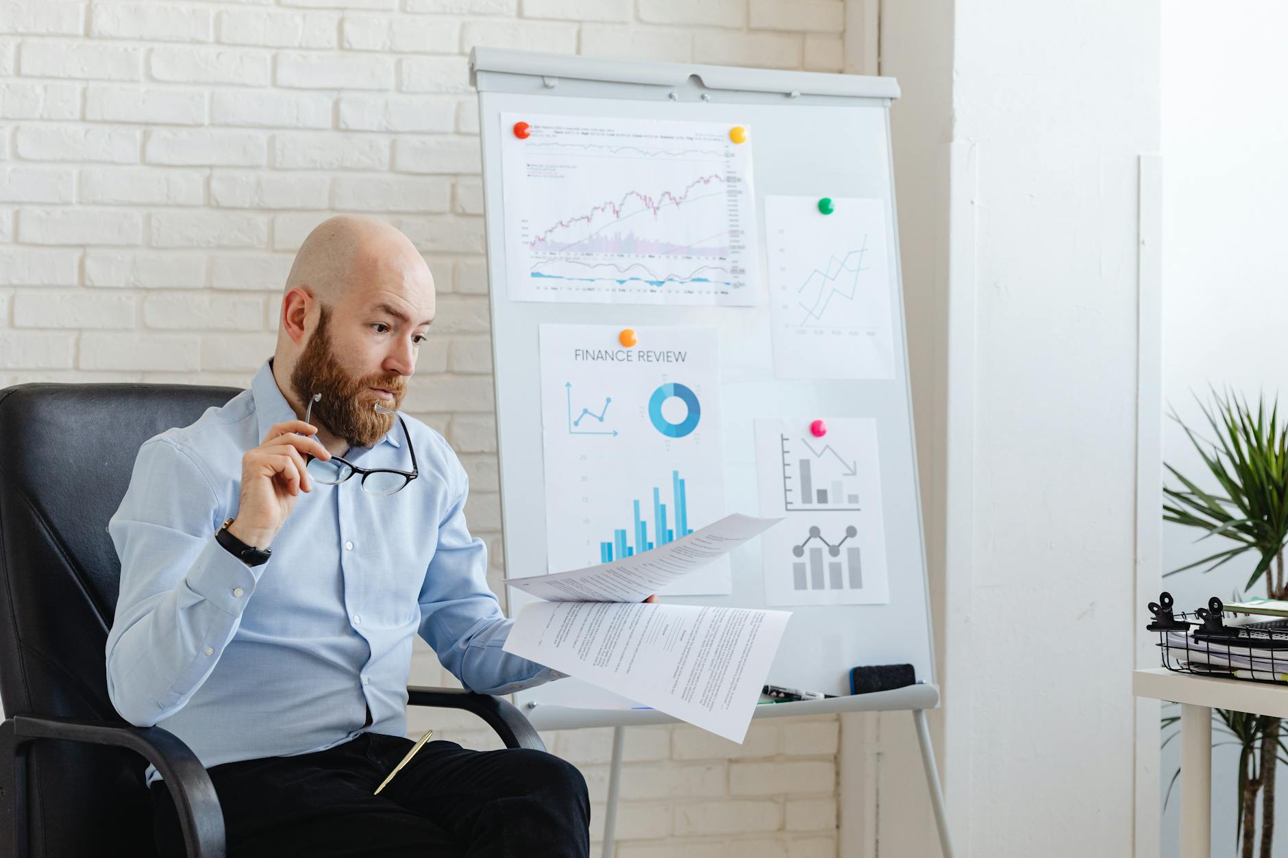 Manager italiano analizza grafici e indici di bilancio in ufficio