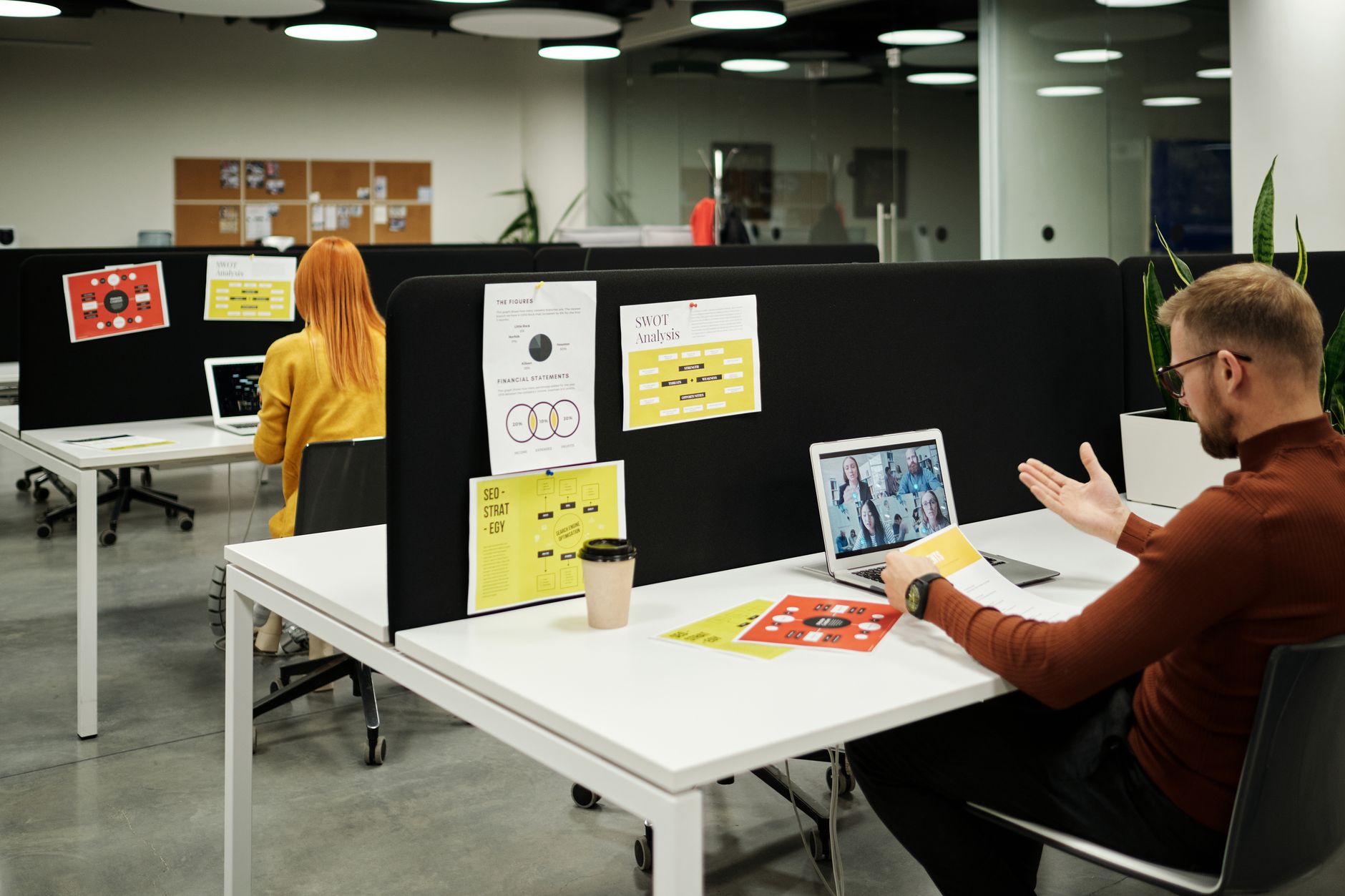 Open space moderno con tavoli condivisi e divani, esempio di ufficio progettato come spazio di collaborazione per modalità ibrida