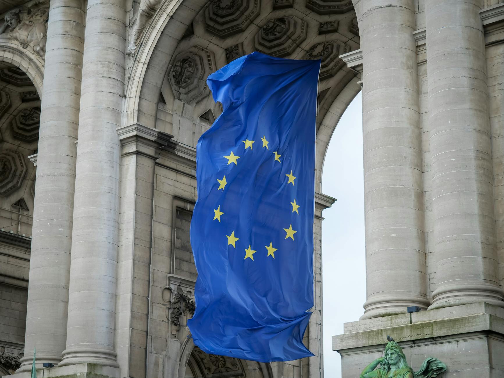 Bandiere europee davanti a edificio istituzionale, riferimento al coordinamento UE su AI e GDPR