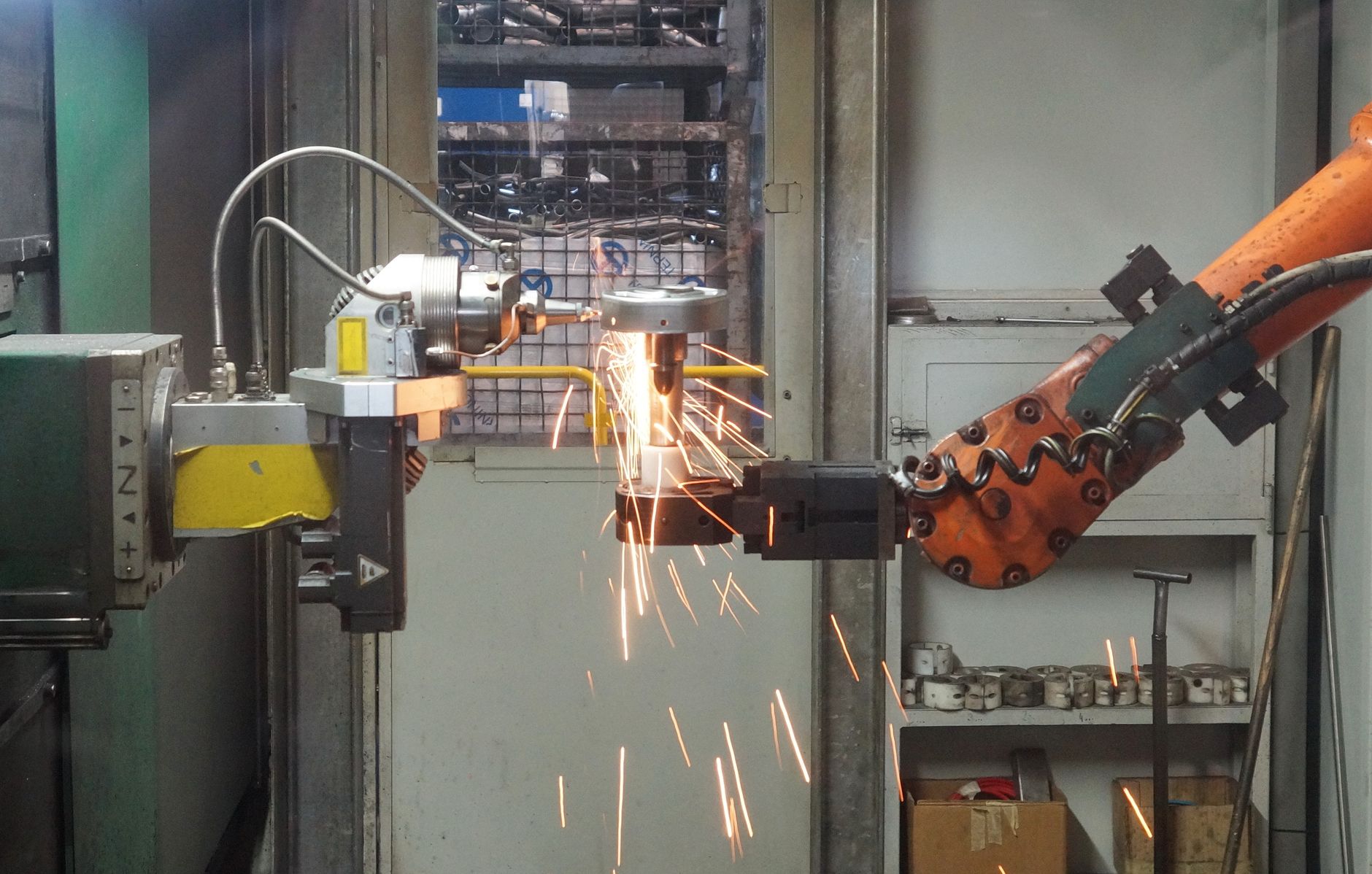 Braccio robotico industriale arancione su linea automatizzata