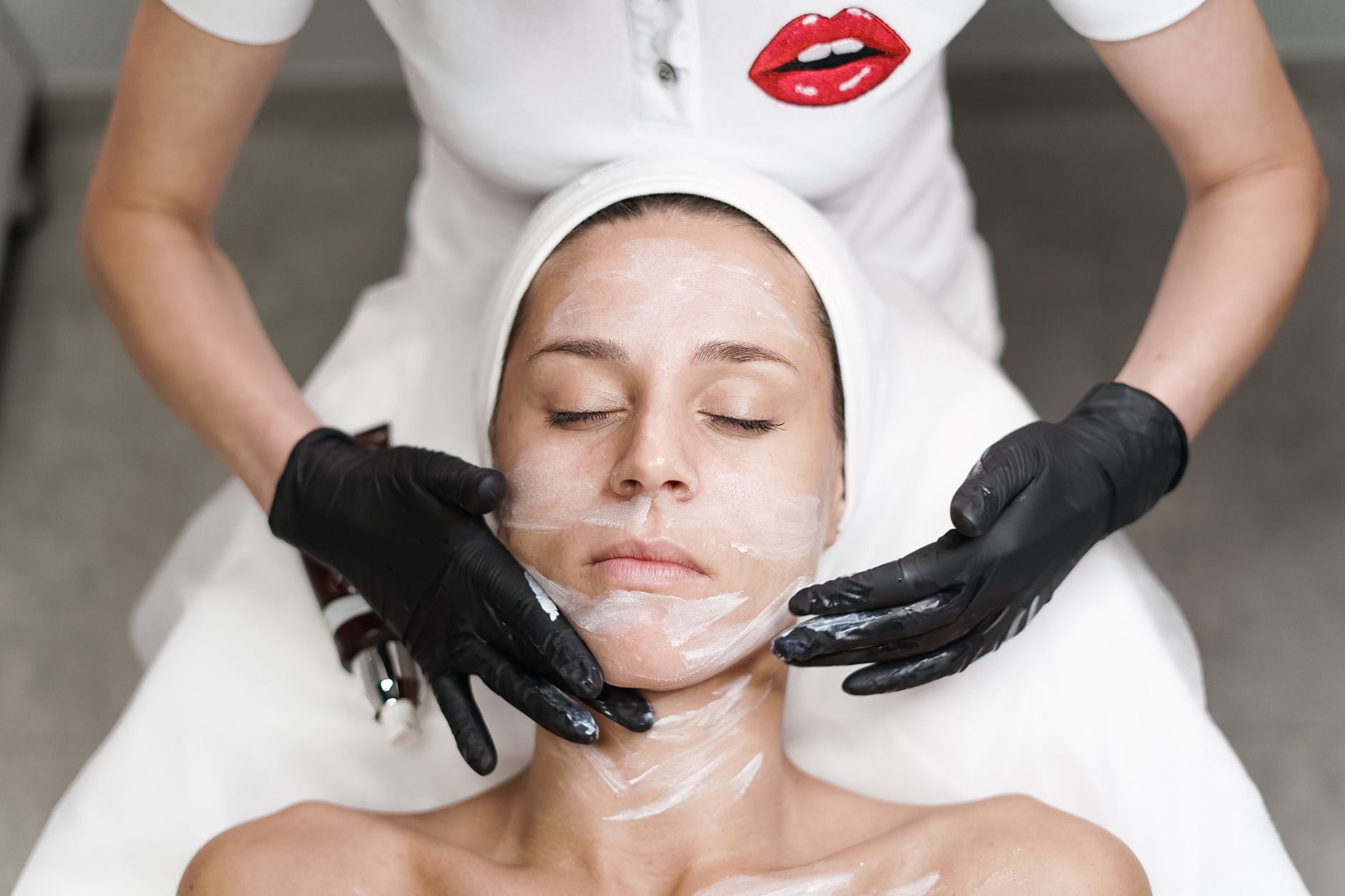 Estetista durante trattamento viso a cliente in cabina insonorizzata