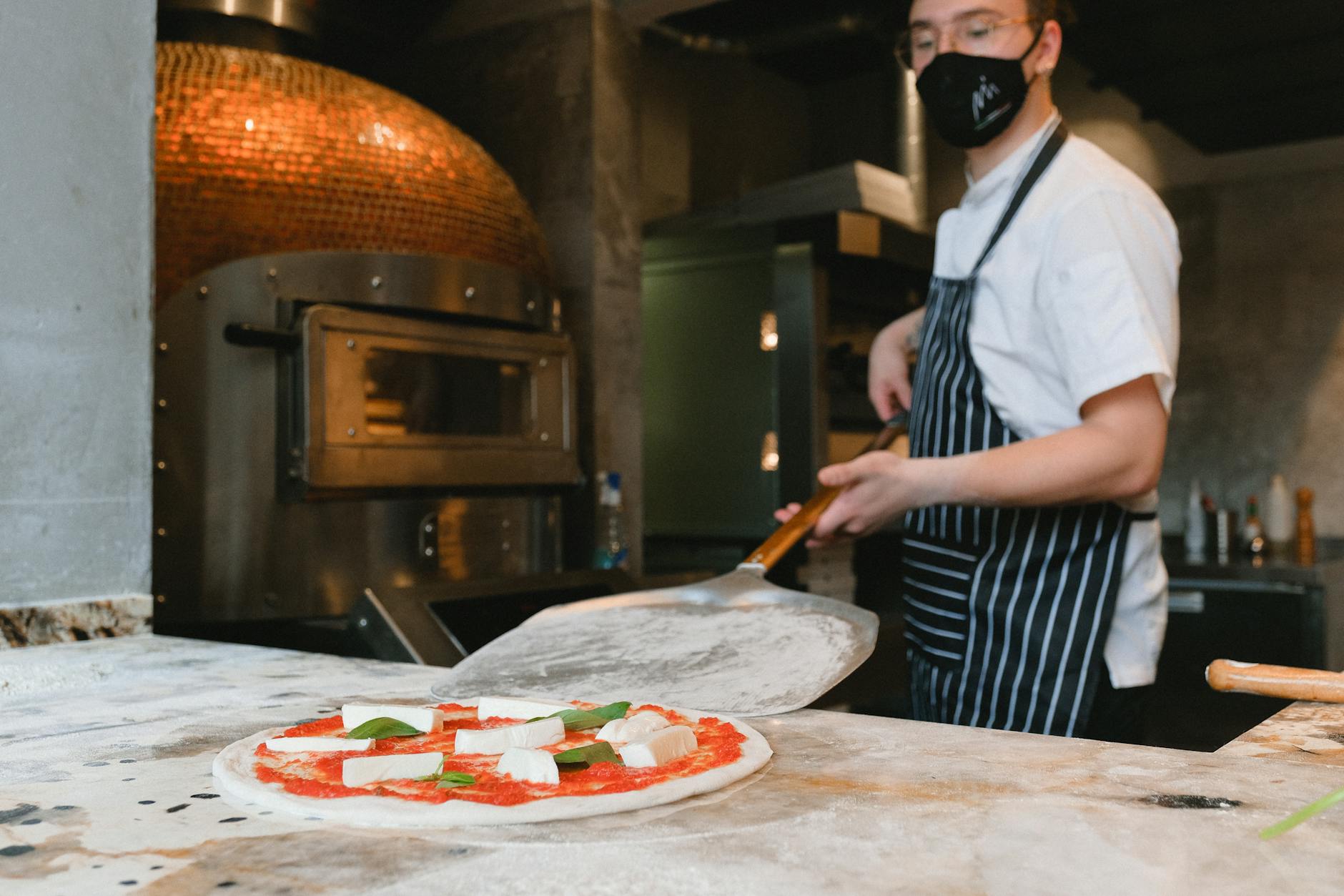Forno a legna di una pizzeria napoletana con pizzaiolo al lavoro