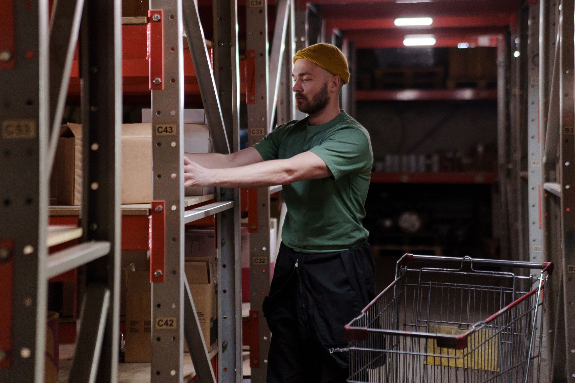 Magazzino con scaffalature alte e operatore picker con dispositivo mobile